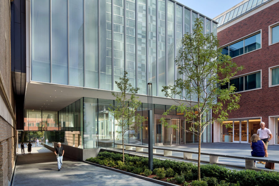Modern glass and brick architecture frame a landscaped courtyard with trees, pathways, and people enjoying the space at the Rothko Pavilion.